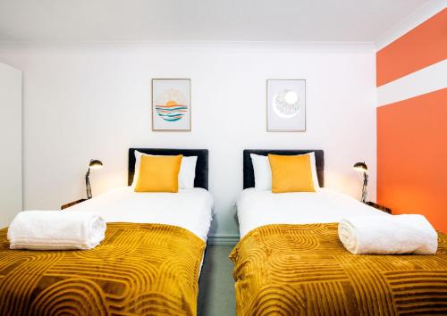 duas camas num quarto com laranja e branco em Southsea Luxury Apartment em Portsmouth