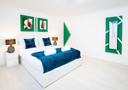 um quarto branco com uma cama grande e lençóis azuis em Southsea Luxury Apartment em Portsmouth