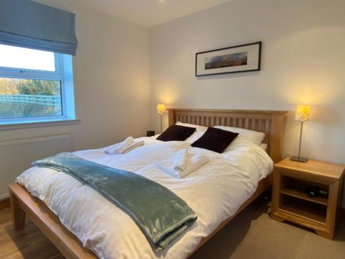 a bedroom with a large white bed with a window at Quinag - luxury villa with sea views in Achiltibuie in Achiltibuie