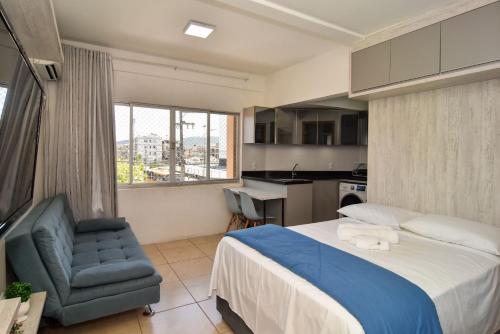 1 dormitorio con 1 cama y 1 silla y cocina en Estudio em frente ao Shopping e Rodoviaria em Balneario Camboriu P891, en Balneário Camboriú