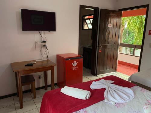 a room with a bed and a desk and a television at Hotel Praia Bonita in Capão da Canoa