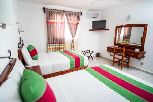 a bedroom with two beds and a desk and a mirror at Hotel Los Olivos Spa in Oaxaca City