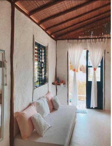 a bedroom with a bed in a room with windows at Eco-Casa Bobô in Ilha de Boipeba