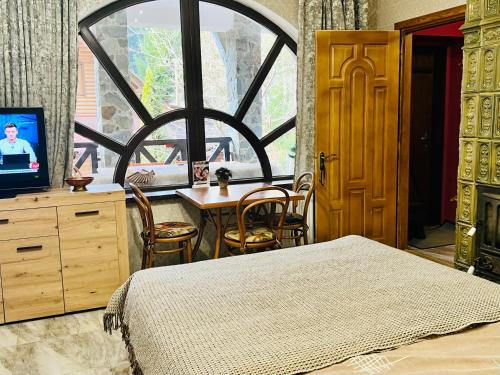 a bedroom with a bed and a table and a window at Вілла Лісова комфорт in Skhidnitsa