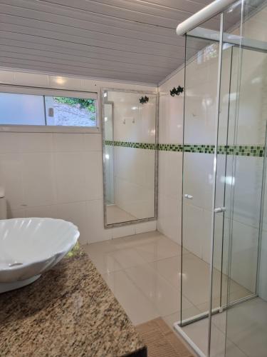 La salle de bains est pourvue d'une douche en verre et d'un lavabo. dans l'établissement Casa do Mato ! Lugar de descanso e Paz !-Next Iguassu Falls, à Foz do Iguaçu