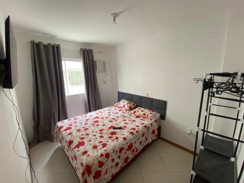 1 dormitorio con 1 cama con manta de flores rojas en Apartamento Aconchegante, en Bombinhas