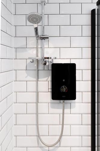 a shower with a speaker on a white tiled wall at Cozy 1BR in Headington Oxford w off-road Parking in Oxford