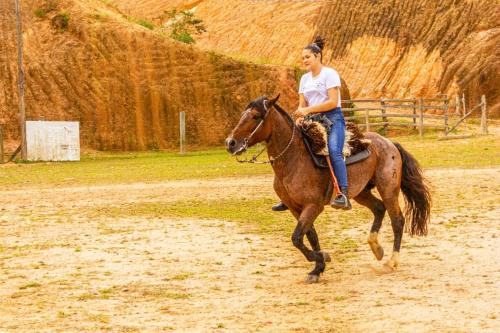 a woman riding a horse on a dirt road at Pousada Casa do Oscar in Governador Celso Ramos