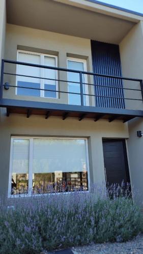 Casa con balcón y flores púrpuras en Duplex Minimalista en Esquel