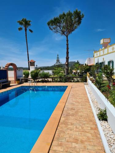 uma piscina num resort com palmeiras em Casa da Mae em Salir