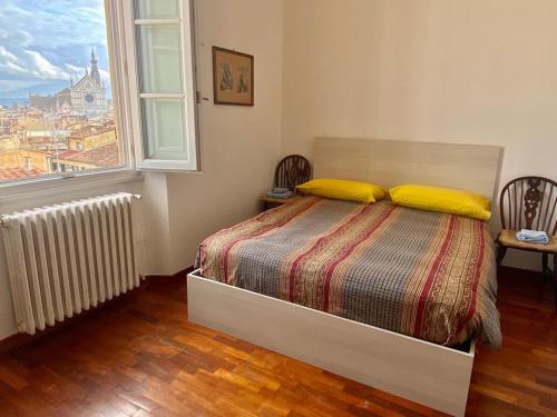 - une chambre avec un lit doté d'oreillers jaunes et d'une fenêtre dans l'établissement Casa Pavó Appartamento accanto al Bargello, à Florence