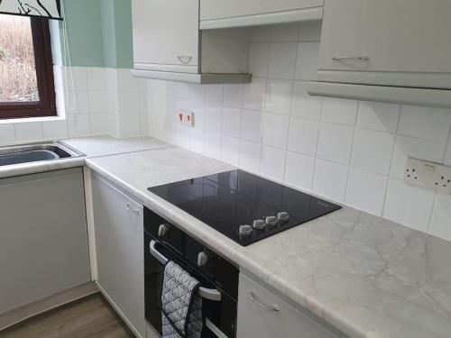 a white kitchen with a stove and a sink at Lovely City Studio near Station. Off Road Parking. in Norwich