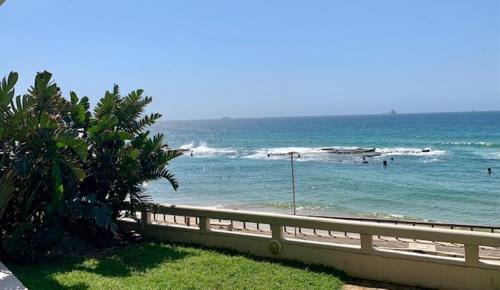 a beach with people in the water and a fence at GARDEN ON THE BEACH in Umdloti