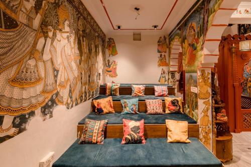 Habitación con almohadas y una pared con pinturas. en Madpackers Pushkar en Pushkar