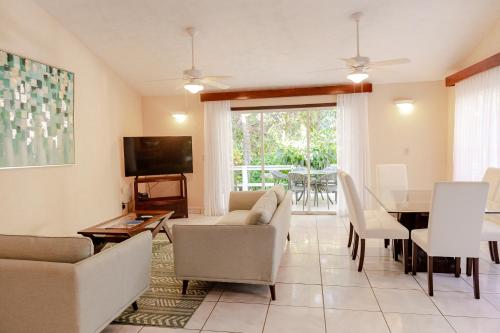 a living room with a table and chairs and a television at Paradise Beach Hotel & Resort in West Bay