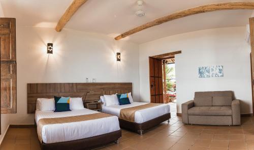 a hotel room with two beds and a chair at Hotel Hacienda La Fe in Bucaramanga