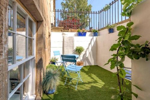 a small patio with chairs and plants on the grass at Lovely 2 Bedroom Garden Flat in trendy West End in Glasgow
