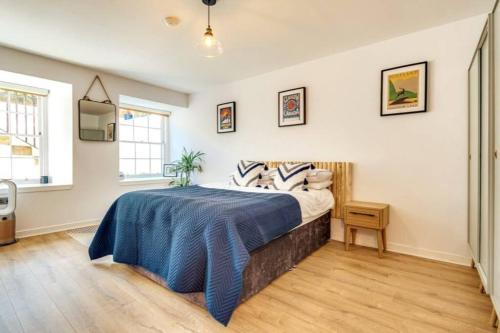 a bedroom with a bed with a blue blanket on it at Lovely 2 Bedroom Garden Flat in trendy West End in Glasgow