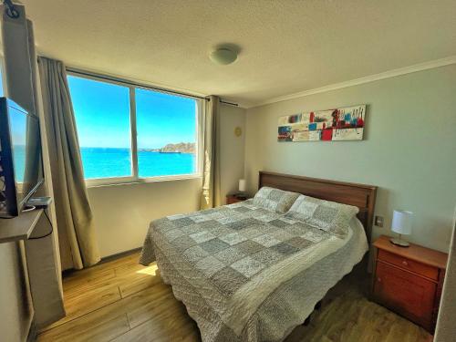 a bedroom with a bed and a large window at DEPARTAMENTO EN PLAYA LA HERRADURA (CONDOMINIO BAHÍA HORIZONTE) +569 95468707 in Coquimbo