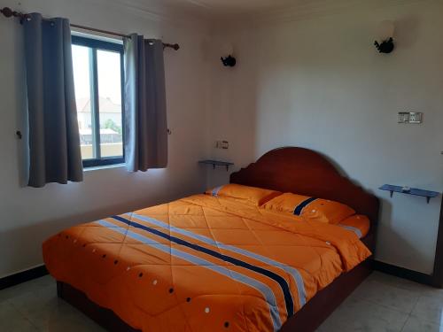 a bedroom with a bed with an orange comforter and a window at Homestay 1-2pax AC room 5 including private kitchen in Siem Reap