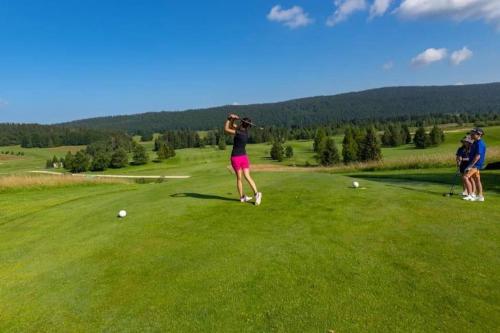 una mujer golpeando una pelota en un campo de golf en Le Chalet, Superbe Duplex 3 étoiles proche du centre des Rousses, 5 personnes, Draps inclus, en Les Rousses