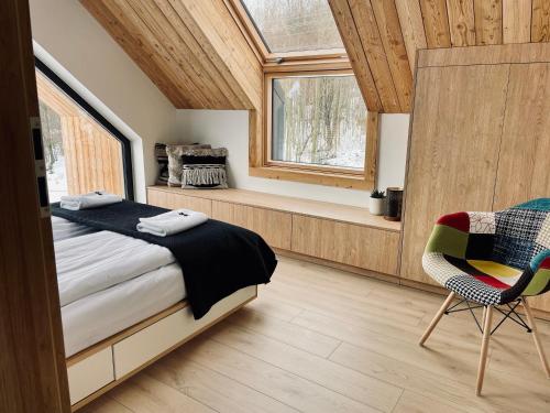 1 dormitorio con cama, ventana y silla en Drwalówka - Domek "POD GRAPĄ", en Grzechynia