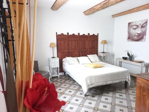 1 dormitorio con 1 cama y una flor roja en el suelo en LA ROSE DES VENTS, en Le Pouget