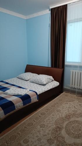 a bedroom with a bed and a blue wall at Гостевой дом Самурук in Atyraū