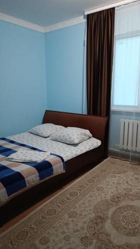 a bedroom with a bed and a blue wall at Гостевой дом Самурук in Atyrau
