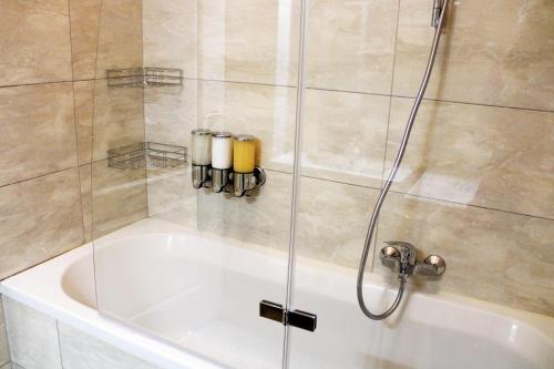 a shower with a glass door next to a bath tub at Goldberger Apartment 1020 in Vienna