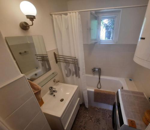 a white bathroom with a sink and a bath tub at Füge Vendégház Csopak in Csopak