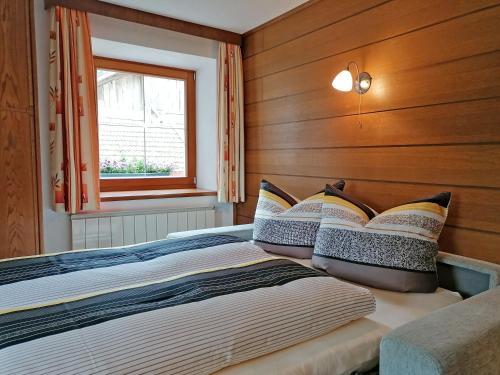 Un dormitorio con una cama con paredes de madera y una ventana en Haus zur Mühle, en Ried im Oberinntal