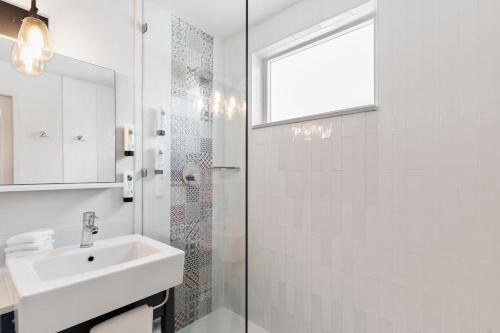 a white bathroom with a sink and a shower at Postcard Inn On The Beach in St Pete Beach