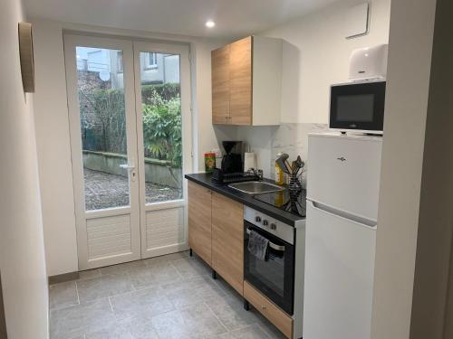 a kitchen with a white refrigerator and a sink at Le Jardin des Caps, proche mer et port in Calais