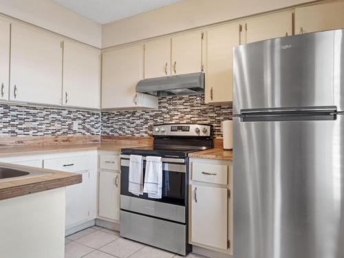 a kitchen with a stainless steel refrigerator and white cabinets at 2 Bedroom-1.5 Bath Apartment Steps away from Beach & Inlet d in Fort Pierce