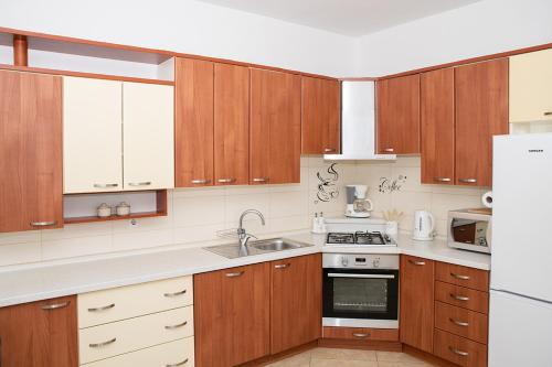 a kitchen with wooden cabinets and a white refrigerator at Apartman Mira i Denis in Rab