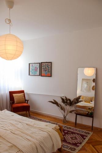 ein Schlafzimmer mit einem Bett, einem Spiegel und einem Stuhl in der Unterkunft Bohome apartman - FREE PARKING in Vranje