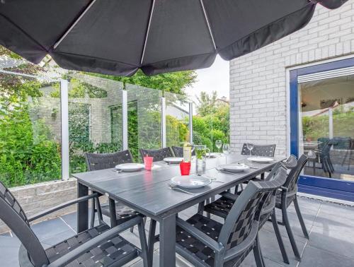 a wooden table with chairs and an umbrella on a patio at Private, 5-star vacation home on a beautiful island in De Cocksdorp