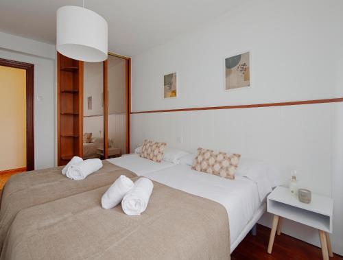 twee bedden in een slaapkamer met twee witte kussens bij 165A Apto moderno 2 dormitorios in Gijón