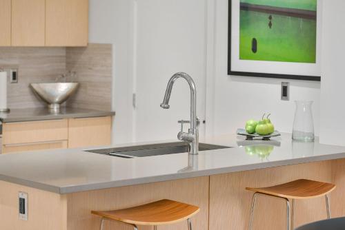 a kitchen with a sink and two bar stools at Duet Executive Stay in Victoria