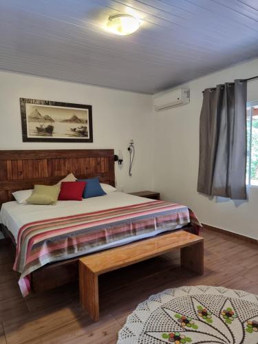 1 dormitorio con cama y banco. en Casa do Mato ! Lugar de descanso e Paz !-Next Iguassu Falls, en Foz do Iguaçu
