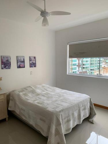 a white bedroom with a bed and a window at Apartamento Capão da Canoa in Capão da Canoa