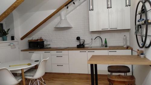 a kitchen with white cabinets and a wooden table at Old Town Loft Apartments in Kamianets-Podilskyi
