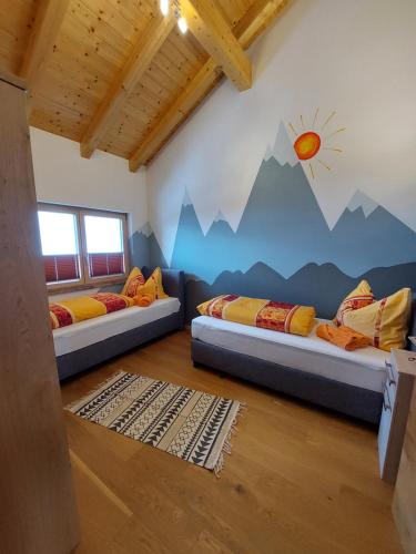 twee bedden in een kamer met een bergmuurschildering aan de muur bij Fewo Baurechthof in Goderschach