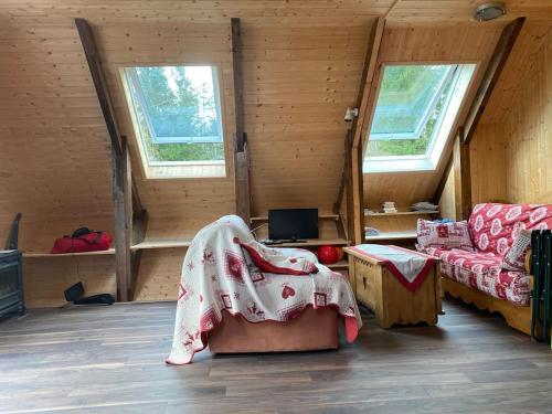 a room with a bed and a couch and two windows at Chalet cosy, belle vue, dans le massif du Vercors in Lans-en-Vercors