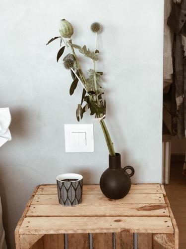 a black vase on a wooden table with a plant at AVLiving City INSIDE NINE Basel in Basel