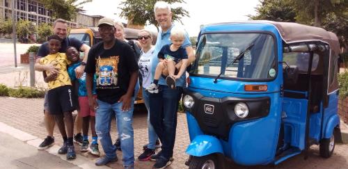 a group of people standing next to a small car at Authentic Bicycle Tours and Backpackers in Soweto