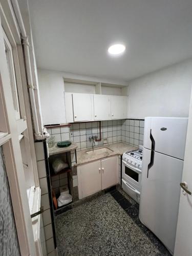 una pequeña cocina con armarios blancos y nevera. en Departamento en el centro de Mar del plata en Mar del Plata