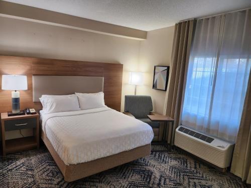 a hotel room with a bed and a desk and a window at Candlewood Suites Harrisburg I-81 Hershey Area by IHG in Harrisburg