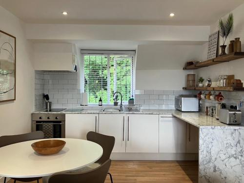 cocina con armarios blancos, mesa y fregadero en Beautiful Annex Apartment with off street parking en Potters Bar